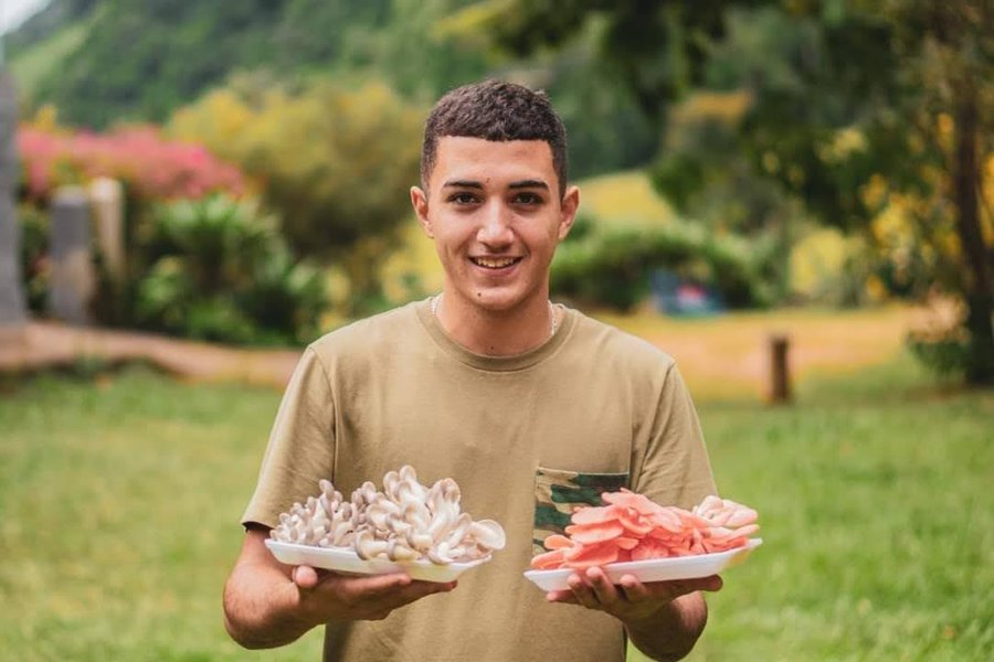 Gustavo segurando dois pratos de cogumelos que produzia na Refazenda