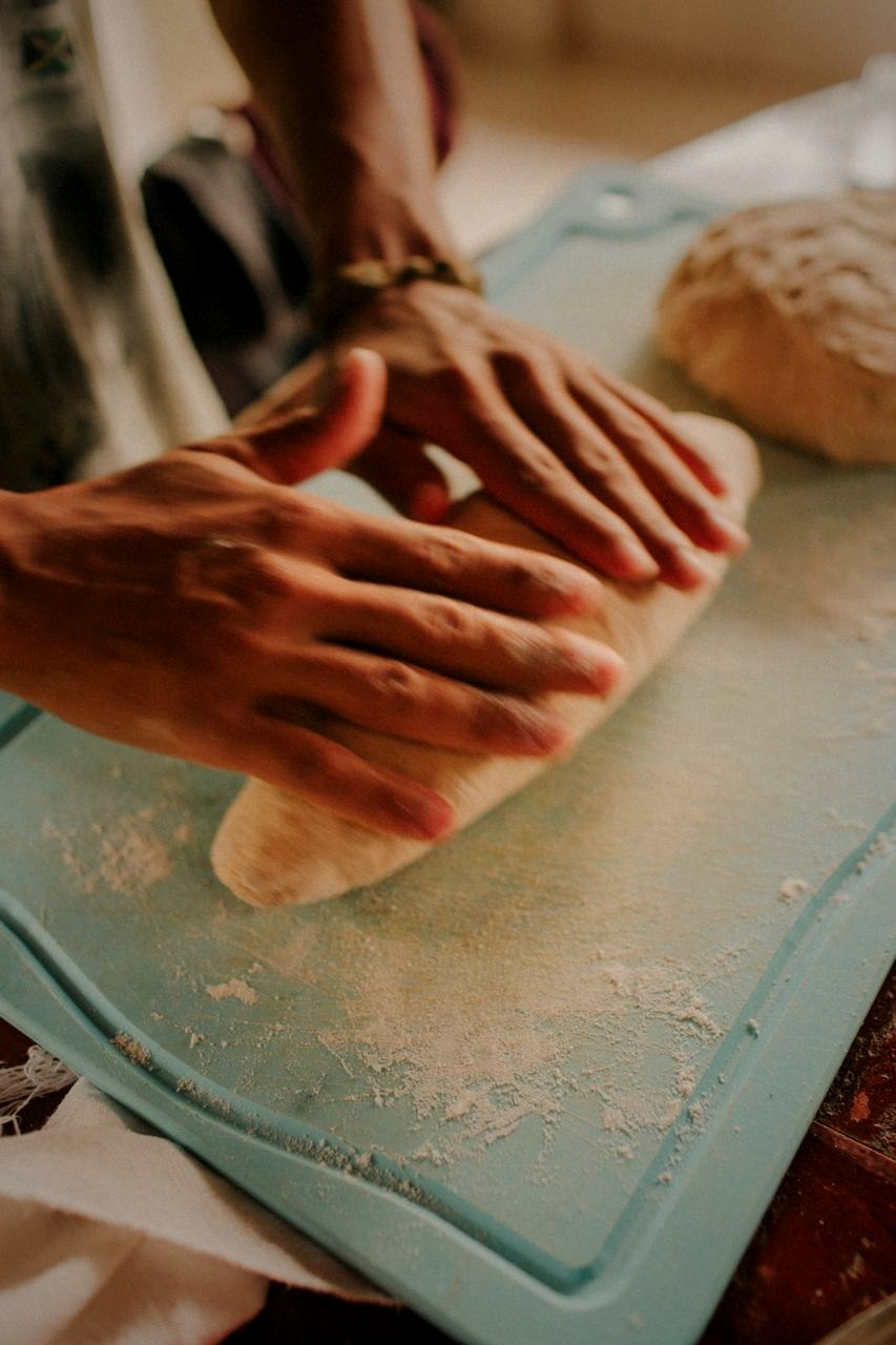 Mãos sovando massa de pão caseiro sobre a bancada