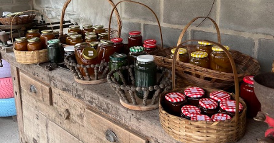Cestas e potes de doces e conservas de diferentes produtores, organizados sobre um balcão de madeira